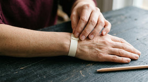 Paper strip held around a bare wrist with its overlapping ends visible.