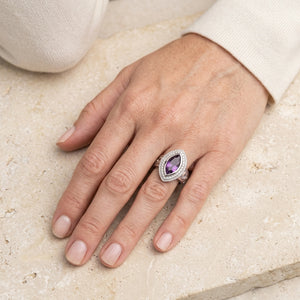 Marquise amethyst crozier silver ring worn on a woman's hand resting on pale stone.