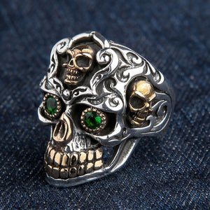 Una vista en ángulo del anillo de calavera barroca, destacando las calaveras doradas laterales y el intrincado trabajo de volutas.