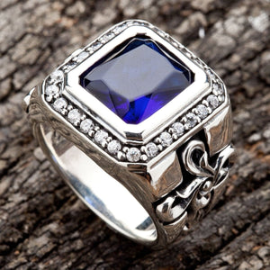 Ein markanter Biker-Ring mit einer Lilie (Fleur-de-Lis), einem großen saphirblauen Stein und einer massiven Ringschiene aus Silber