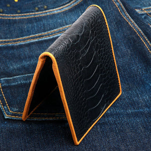 Black Ostrich Leg Bifold with Tan Trim showing the broad ostrich-leg scales and tan edge, standing upright.