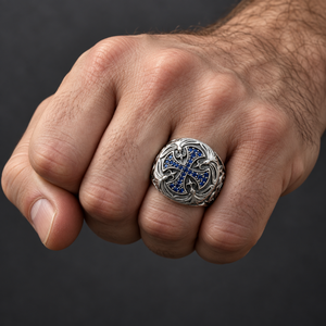 Blue-stone medieval cross silver ring worn on a light-skinned man's clenched fist