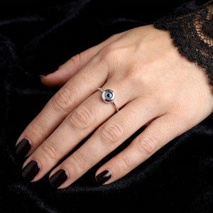 Minimalist blue evil eye ring on a gothic-styled woman's hand