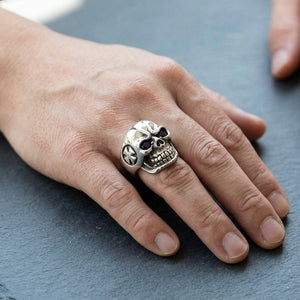 Bague tête de mort aux yeux bleus en argent sterling 925 portée sur une main d'adulte