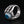 Anillo de plata esterlina con garra esquelética y ojo azul, vista en ángulo del anillo motero con ojo, destacando la textura detallada y el acabado pulido