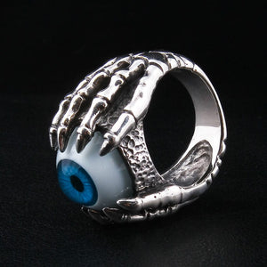 Anillo de plata esterlina con garra esquelética y ojo azul, vista en ángulo del anillo motero con ojo, destacando la textura detallada y el acabado pulido