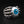 Anillo de plata esterlina con garra esquelética y ojo azul, vista lateral del anillo de ojo con mano esquelética, que detalla los dedos óseos pulidos y los nudillos