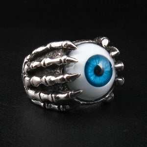Anillo de plata esterlina con garra esquelética y ojo azul, vista lateral del anillo de ojo con mano esquelética, que detalla los dedos óseos pulidos y los nudillos