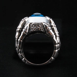 Anillo de plata esterlina con garra esquelética y ojo azul, vista cenital del anillo con ojo azul, mostrando el iris vívido y las afiladas garras que rodean