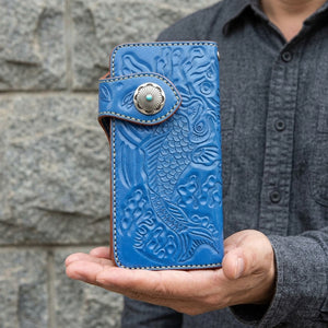 Blue koi carp tooled leather wallet with turquoise-center concho, held upright on an open palm