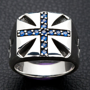Un anello con croce di Malta in argento sterling massiccio, intarsiato con brillanti pietre blu, mostrato su uno sfondo scuro e strutturato