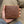 Brown quill ostrich bifold with tan edging supported in a hand above a khaki-clothed lap.