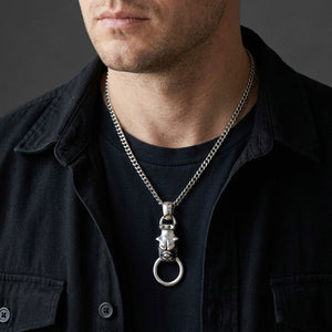 Sterling silver bulldog pendant with a mouth ring worn over a black shirt, framed from the lower face to the chest.
