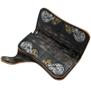 Portefeuille long en cuir noir à motif tête de mort et os sculptés, intérieur ouvert avec fentes pour cartes et décorations têtes de mort