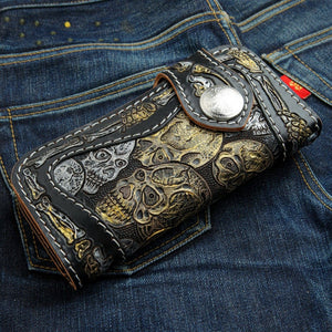 Portefeuille long en cuir noir à motif tête de mort et os sculptés, portefeuille aux têtes de mort orienté sous l'angle opposé sur denim