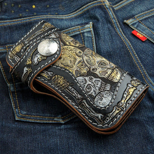 Portefeuille long en cuir noir à motif tête de mort et os sculptés, portefeuille fermé à bouton-pression posé en biais sur du denim