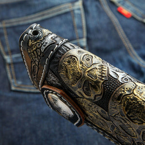 Portefeuille long en cuir noir à motif tête de mort et os sculptés, gros plan latéral sur le cuir orné et le bord surpiqué