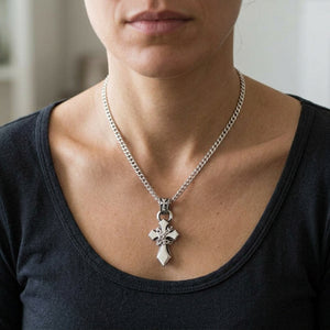Colgante de cruz con cadena de plata de ley llevado con una cadena de plata y una camisa oscura