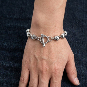 Bracelet épais à maillons têtes de mort en argent sterling 925 porté autour d'un poignet adulte