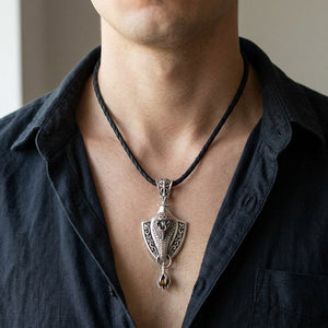 Cobra-schildhanger met leren ketting, gedragen aan een ketting met hals en bovenborst zichtbaar