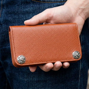 Cognac Brown Cowhide Leather Wallet, closed front held on dark denim