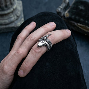 Coiled sterling silver snake ring on a relaxed hand, with raised scales, a pointed tail and small black eyes.