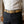 Cintura in pelle di coccodrillo hornback crema indossata nei passanti di pantaloni scuri