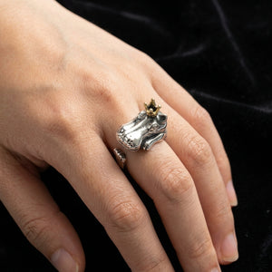 Bague ajustable en argent avec hippopotame couronné portée sur une main contre du velours noir