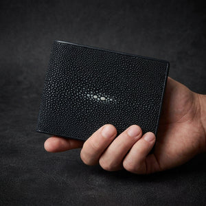 Man holding large dark blue polished stingray leather bifold wallet