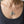Guadalupe and sugar skull oval medals worn together on a silver chain above a charcoal scoop-neck shirt.