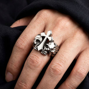 Anillo de plata con doble calavera y cruz llevado en una mano