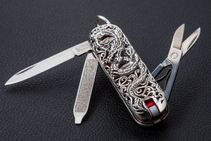 Open dragon silver multi-tool showing knife blade, file and scissors