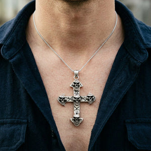 Five-skull silver cross pendant on a chain, shown against a male neck and chest