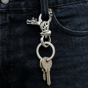 Flame dragon silver keychain clipped to a belt loop, with keys on the round ring below