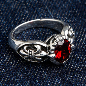 Red red stone fleur de lis gothic ring in 925 sterling silver with ornate scrollwork on blue denim background