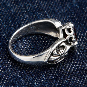Three quarter view of fleur de lis red stone ring highlighting gothic scrollwork and gemstone setting