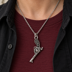 Flintlock Pistol and Heart Sterling Silver Pendant hanging barrel-down over a burgundy shirt.
