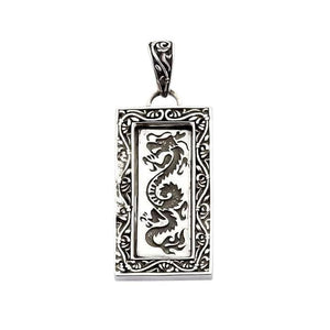 Ciondolo rettangolare in argento con motivo a drago scuro, bordo a volute floreali e contromaglia affusolata decorata.