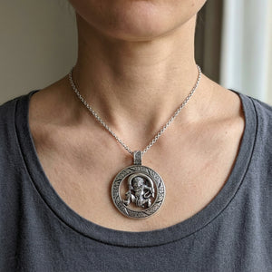 Fujin windgod medaille hanger van sterling zilver, getoond om de hals van een volwassen model; koord of ketting is stylingcontext