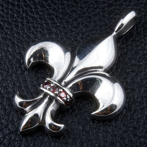 Fleur-de-Lis-Anhänger aus Sterlingsilber mit Granat, Ansicht der Lilie und der roten Steine schräg von links