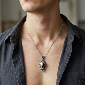 Doodshoofd hanger van .925 sterling zilver met granaatogen, gedragen aan een ketting waarbij hals en bovenborst zichtbaar zijn