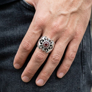 Bague croix tribale en argent sterling avec grenat portée sur une main d'adulte, montrant les détails de face et d'épaulement.