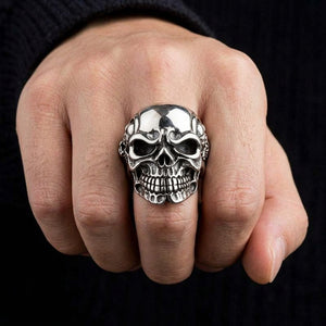 Gigantic skull silver ring showing both eye sockets and teeth on a hand