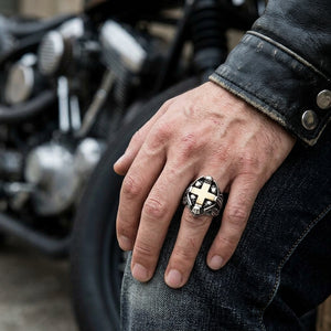 Gold cross and skull silver ring worn on a biker-style hand