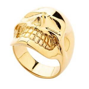 Anillo de calavera de latón bañado en oro de 14k, ángulo bajo que muestra la calavera en relieve y la banda sobre fondo blanco