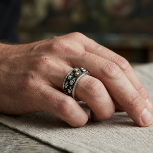 Anillo giratorio de plata de ley .925 con calavera dorada llevado en una mano