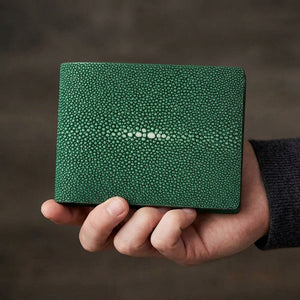 Green polished stingray bifold wallet held in one hand