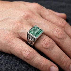 Green stone square eagle and lion silver signet ring shown clearly on a hand in close detail