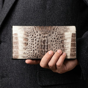 Grey two-tone crocodile hornback long wallet held naturally against a dark jacket