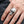 Hamrad punk-dödskallering i sterlingsilver buren på en vuxen hand, visar detaljer på framsidan och ringskuldran.